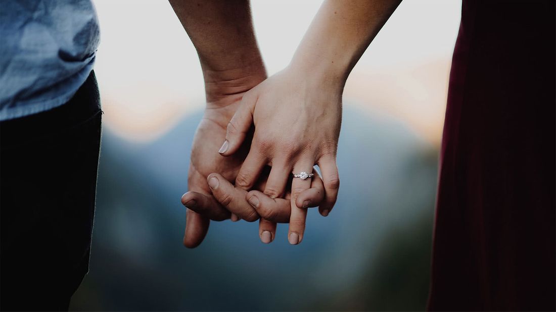 Engaged couple holding hands wondering how much an engagement ring costs