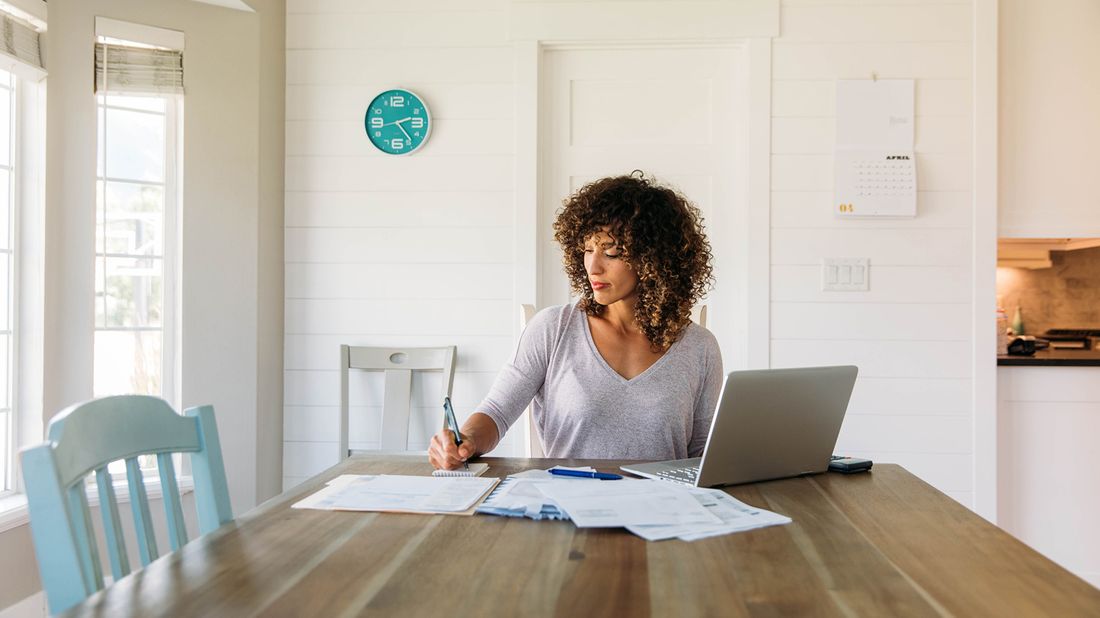 Woman doing taxes at kitchen table and getting a tax extension.