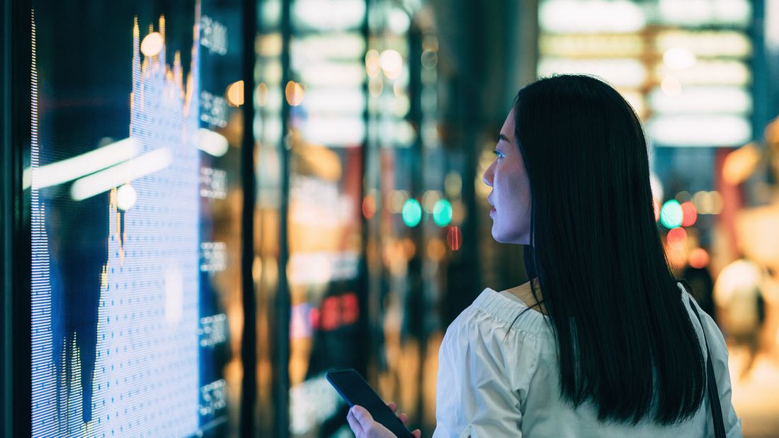 A young woman checking out stock charts from the street