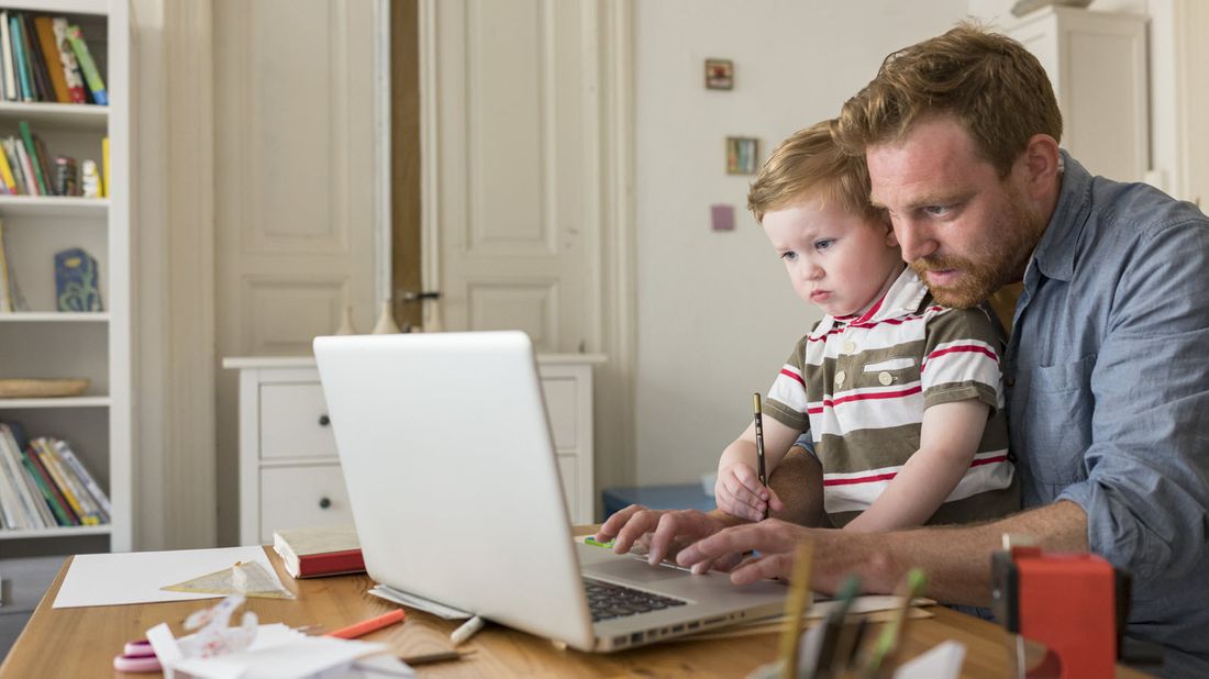 A man working from home with his son in his lap