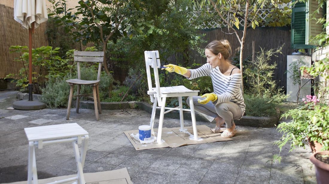 Woman painting a chair in a garden