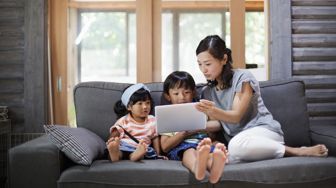 Mom on couch managing kids screen time