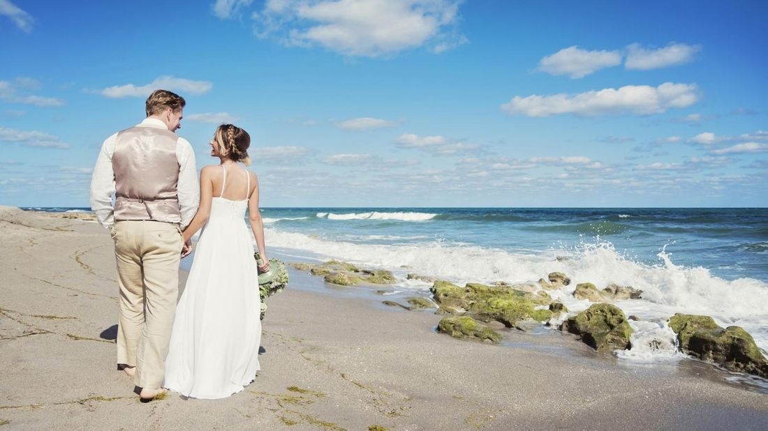 bride and groom walking on a beach