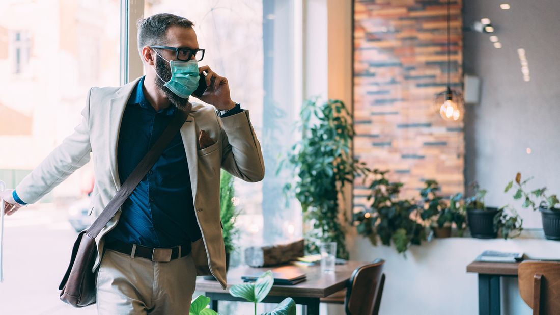 man walking into his office while wearing a mask