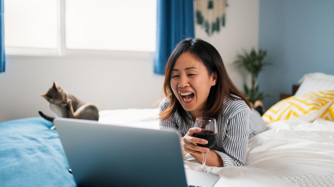 Woman drinking wine on video conference trying to stay social while social distancing.