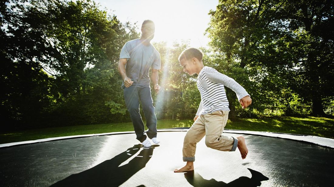 Father and young son jumping on trampoline