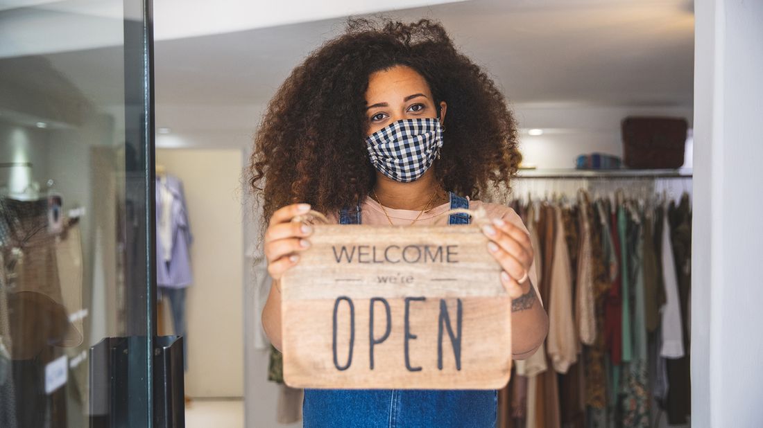 woman holding “Open” sign in a small business