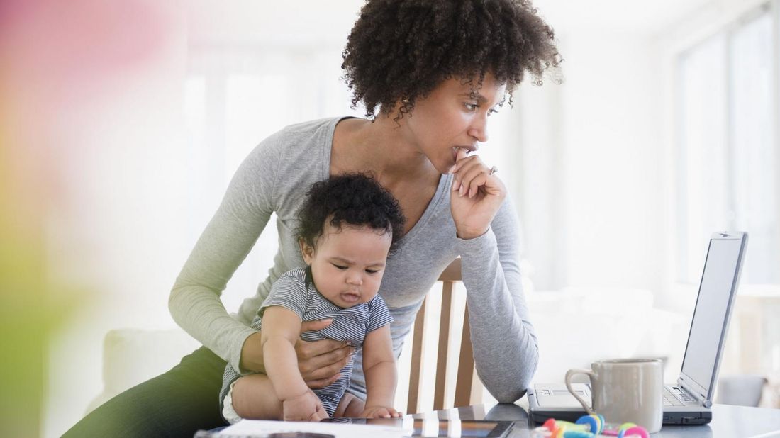 mother holding baby while paying hospital bill on laptop