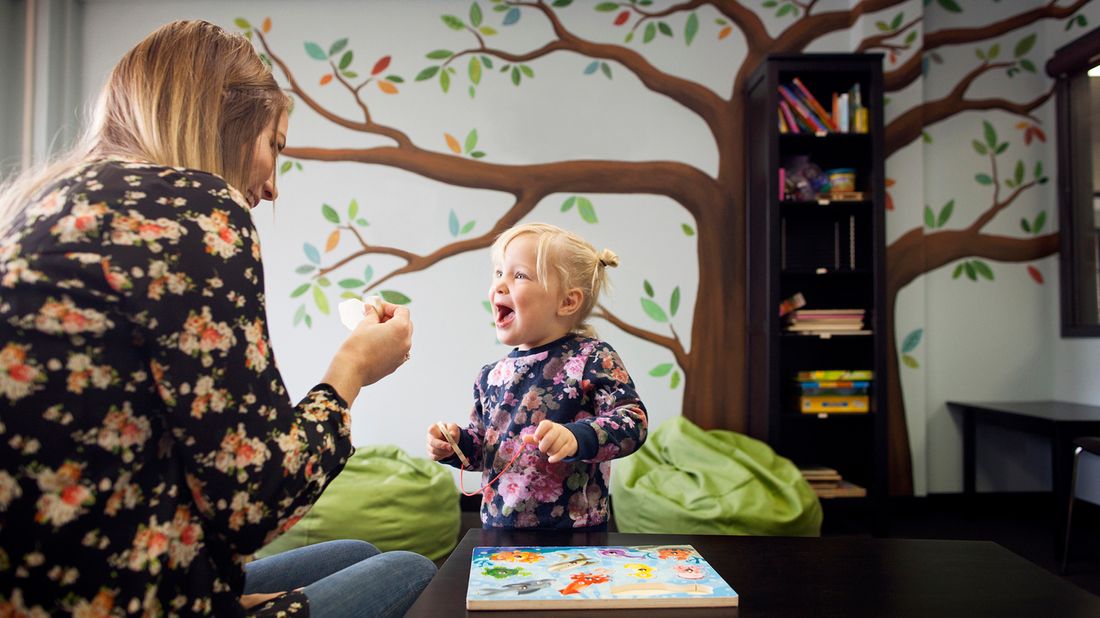 nanny playing with small child in playroom