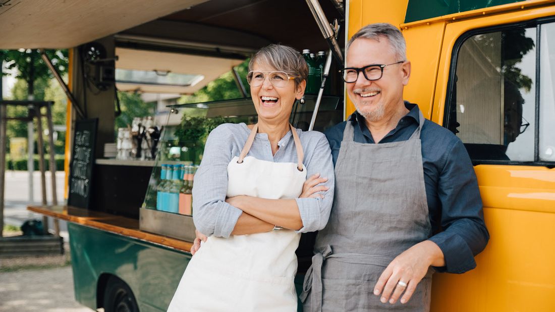 Happy couple standing by a truck after learning how universal life insurance works. 