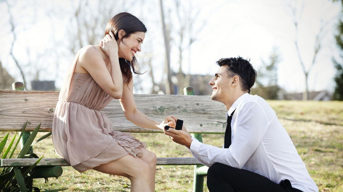 man proposing to woman in park with alternative engagement ring