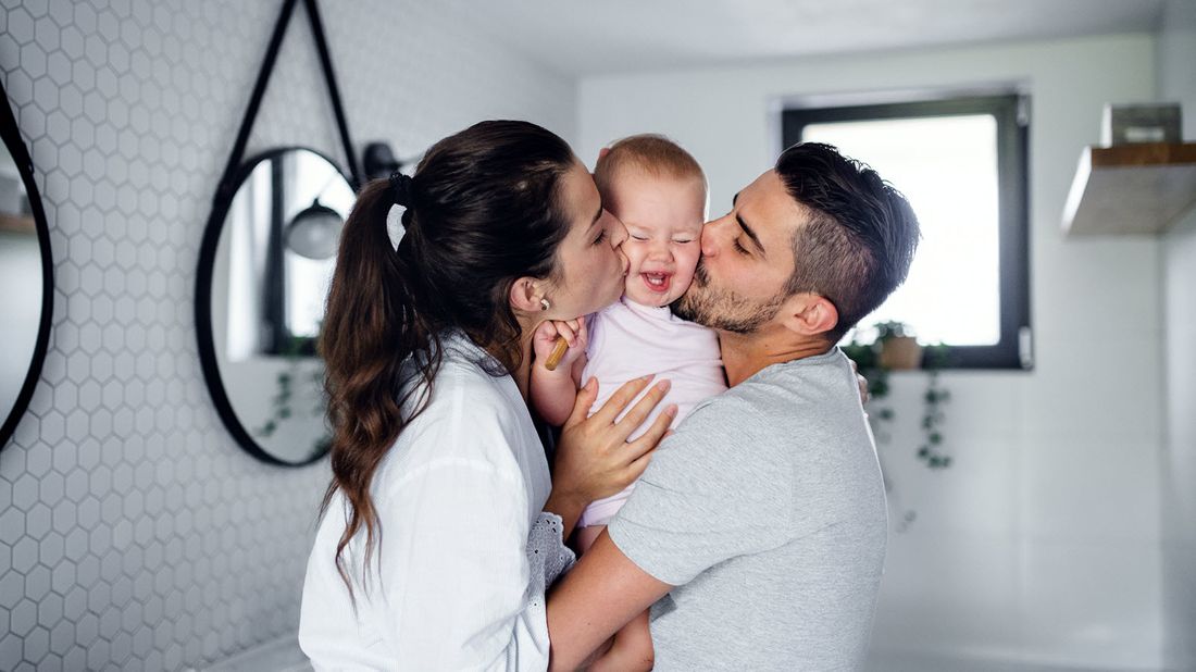 Couple who may need more than one life insurance policy kissing their baby