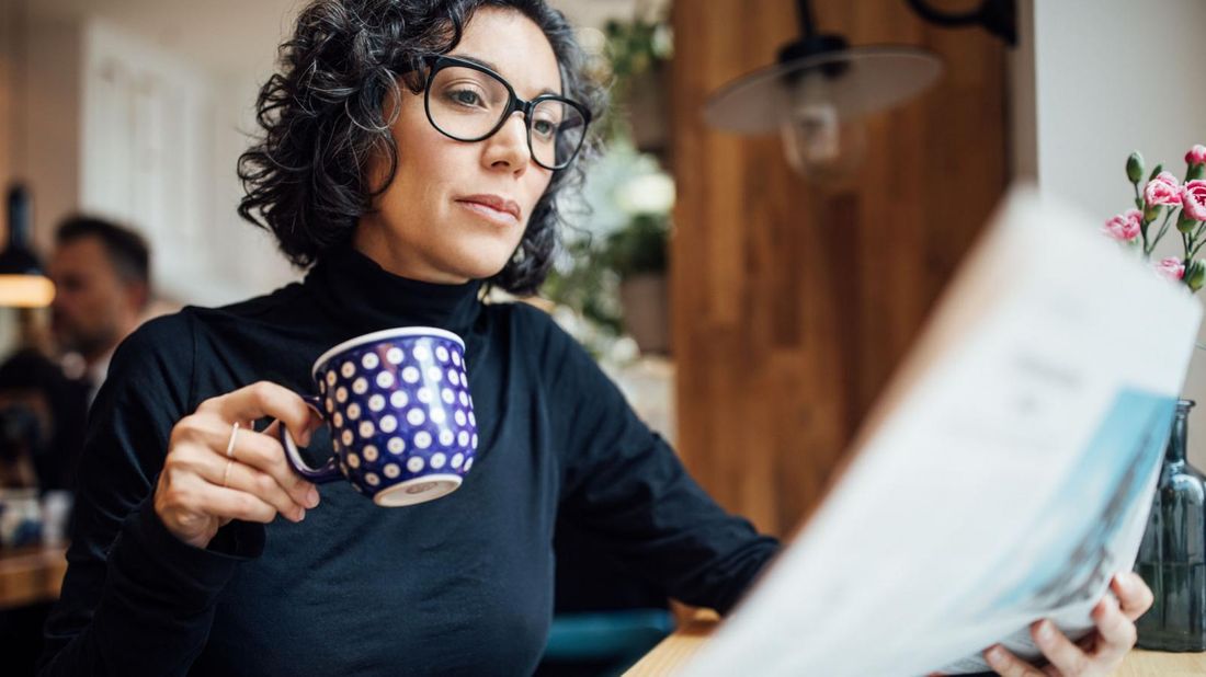 woman reading newspaper article about new COVID relief package