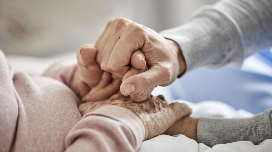 Caregiver holding hands with nursing home patient