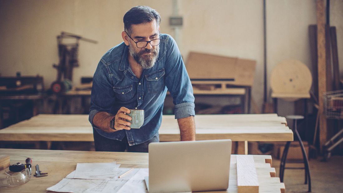 man looking at laptop while working in workshop