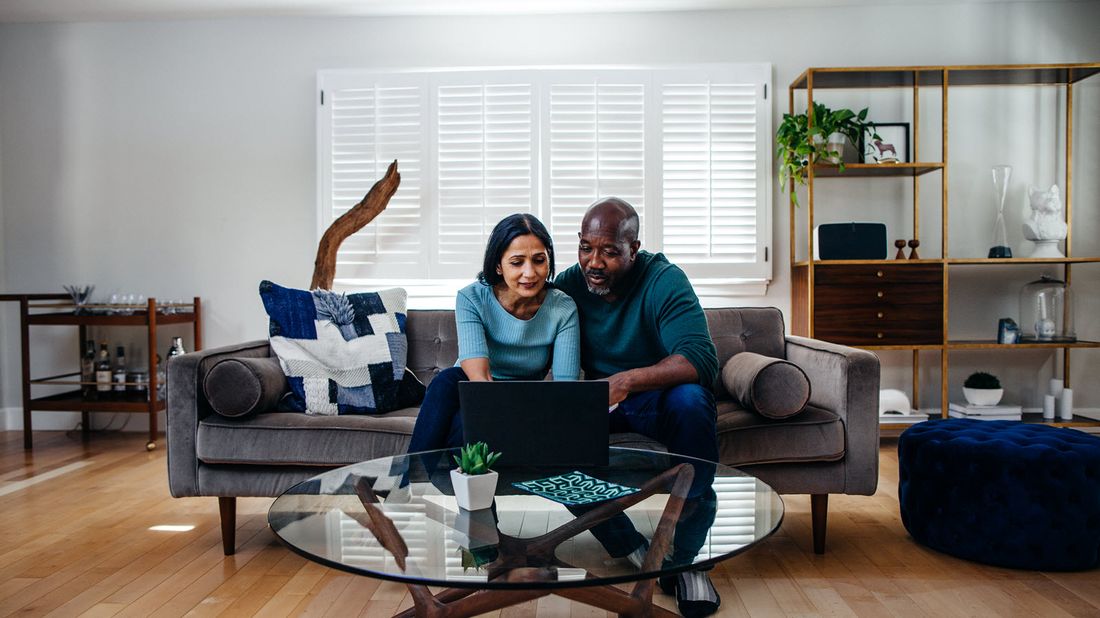 Couple on a couch researching how much money you need for wealth management services.