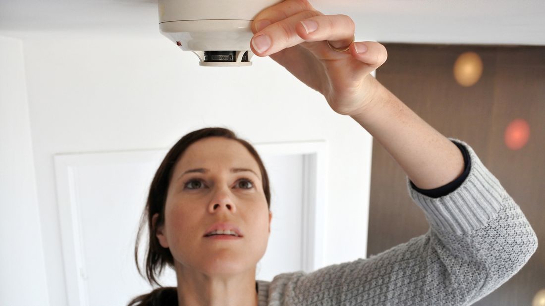 woman checking smoke detector