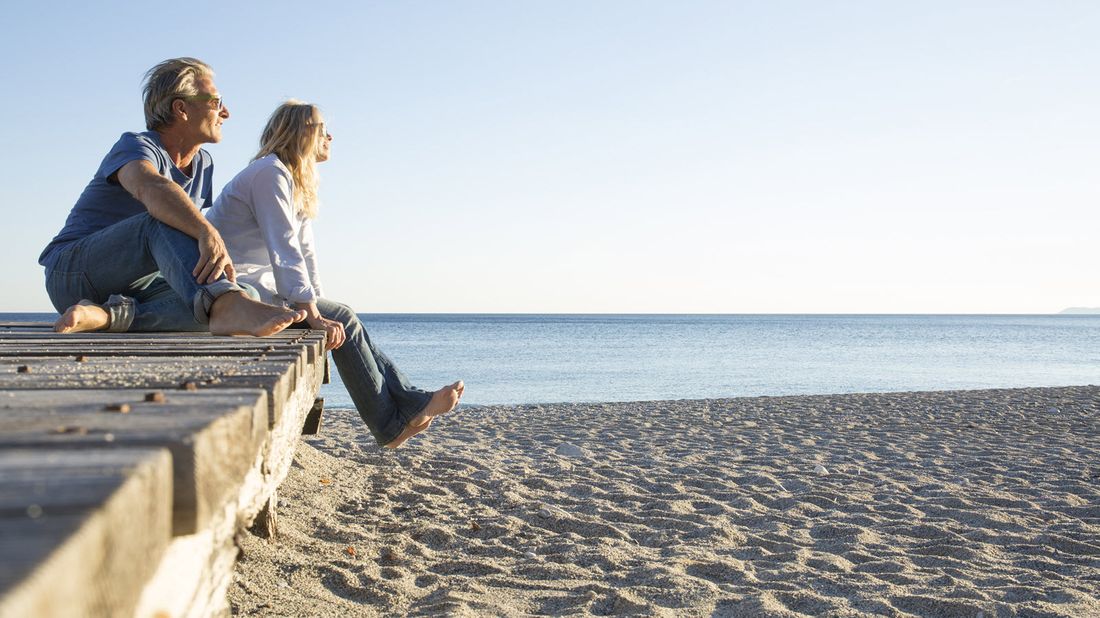 Couple sitting on a pier at a beach wondering how an annuity is taxed.