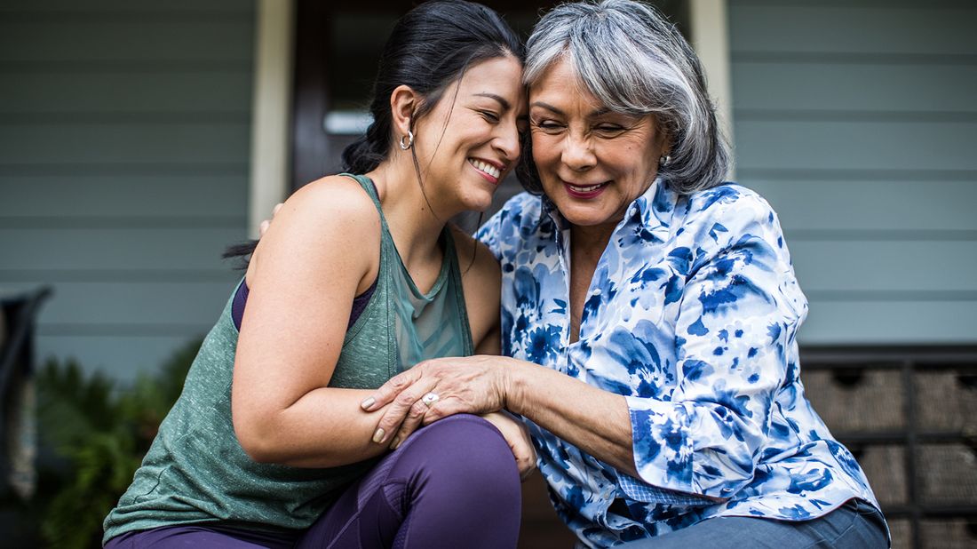 Woman and elderly mom hugging.