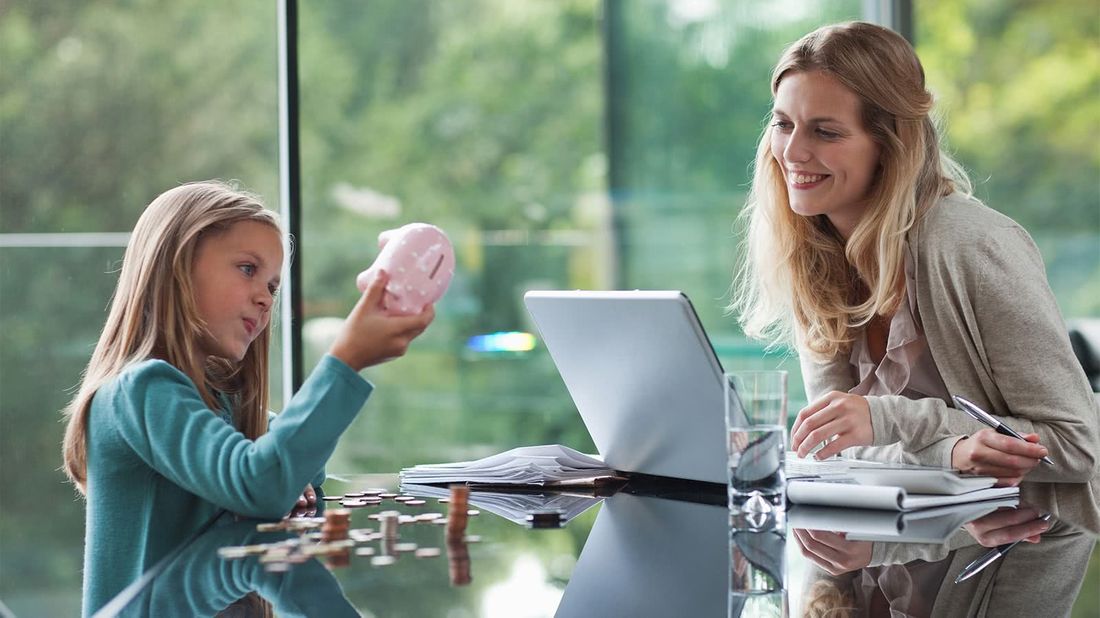 Mother teaching daughter with piggy bank about investing