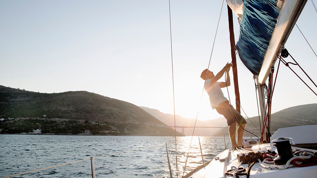 man hoisting sail on boat