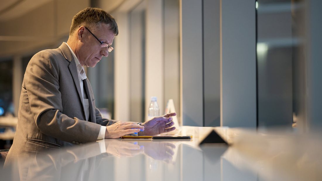 man sitting at a table and reviewing investments portfolio on a mobile device