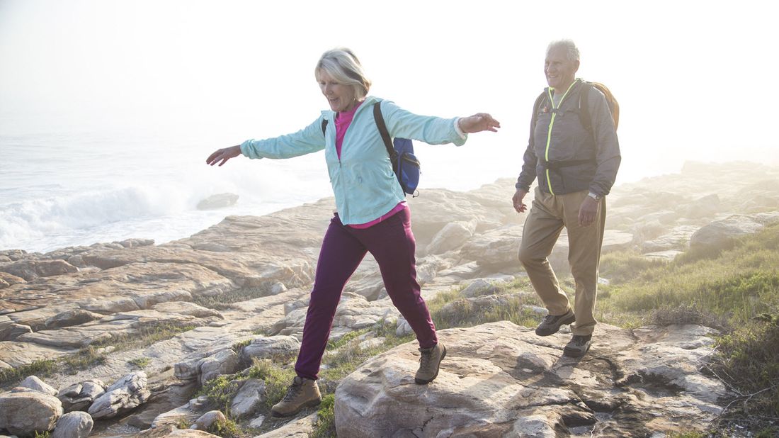 Active retired couple enjoying a hike over a rocky shoreline