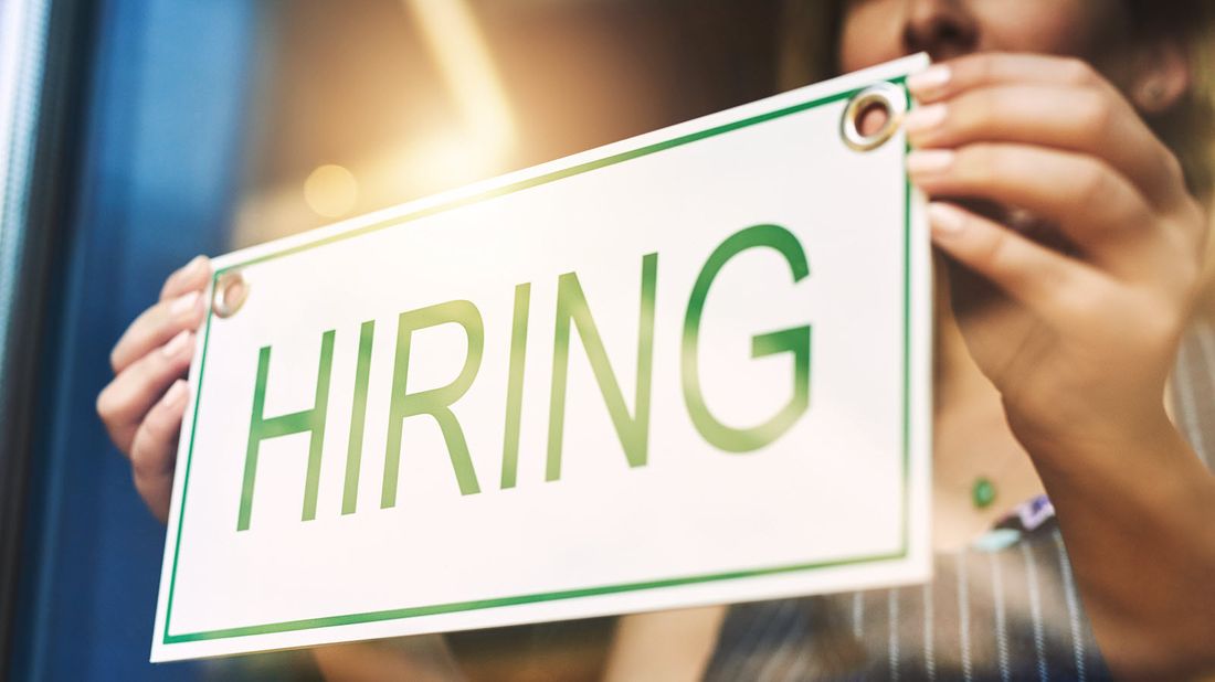 Woman business owner with a hiring sign in her window