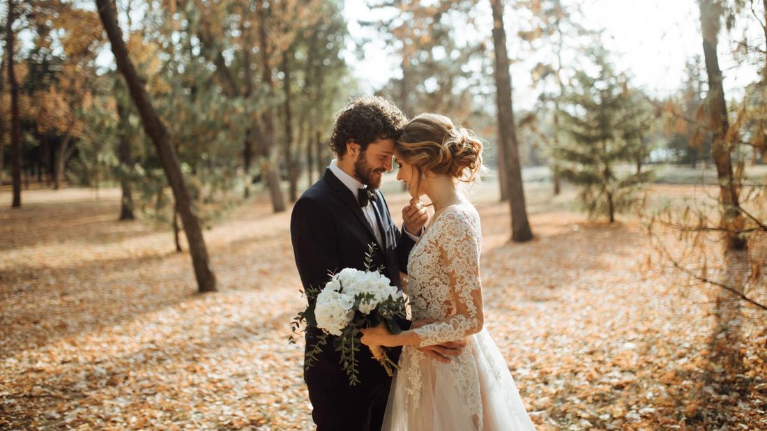 bride and groom getting married in a forest in fall who have negotiated with wedding vendors