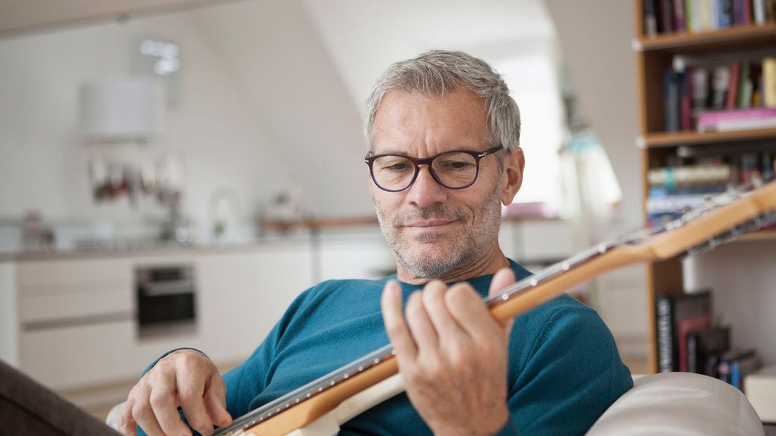 man learning to play guitar as a new hobby