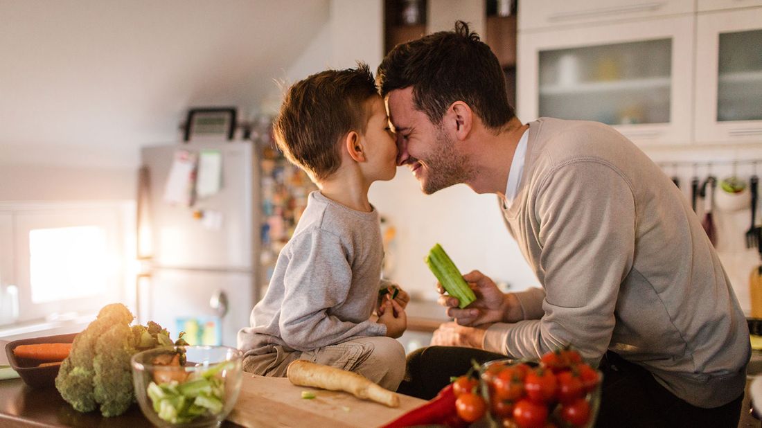 Father and young son in kitchen talking about money topics