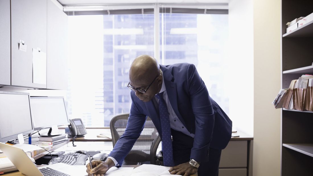 Man reviewing his physical and digital paperwork to see what he should keep and what he should toss.