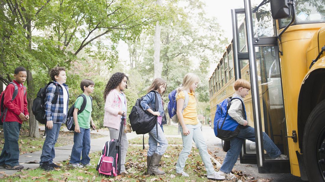 Kids getting on a bus as they head back to school.