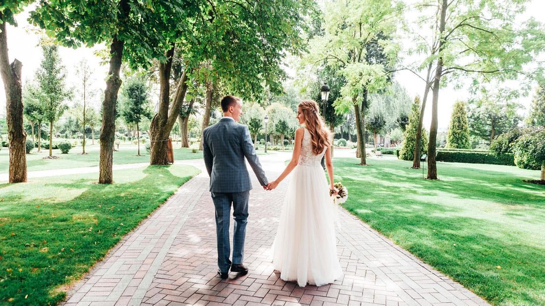 Happy couple walking down a path after their wedding