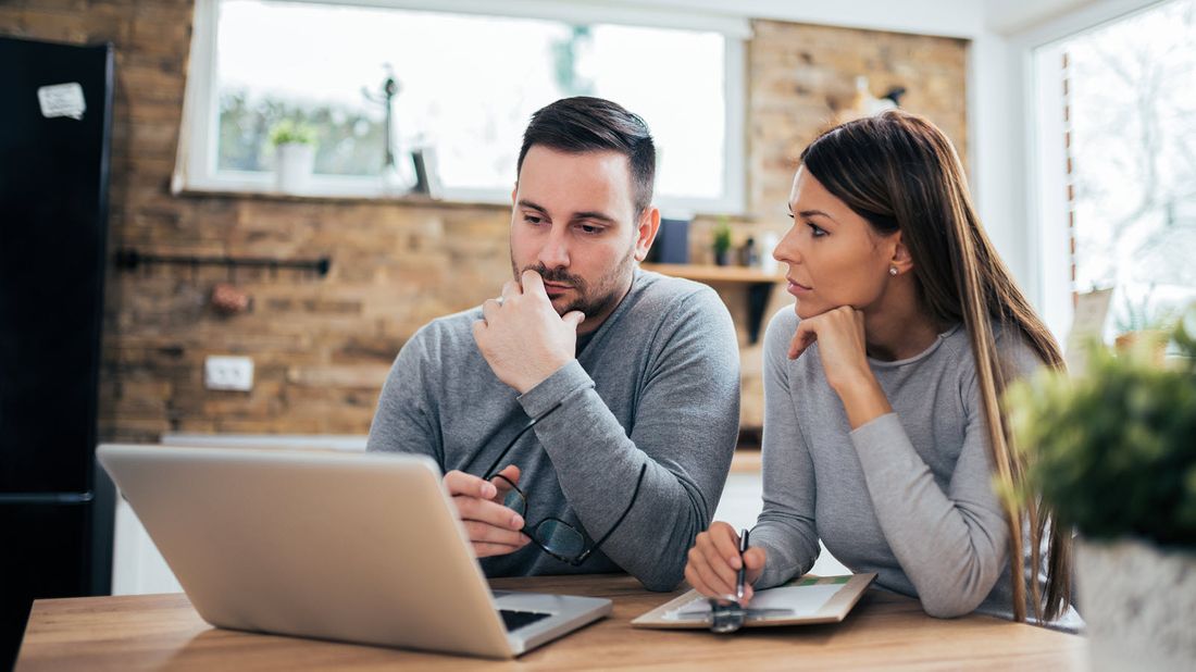 Husband and wife looking at computer reading tips for financial uncertainty. 