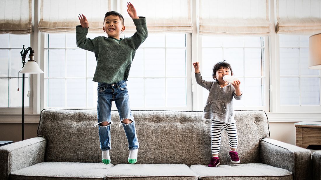 brother and sister jumping on the couch playfully