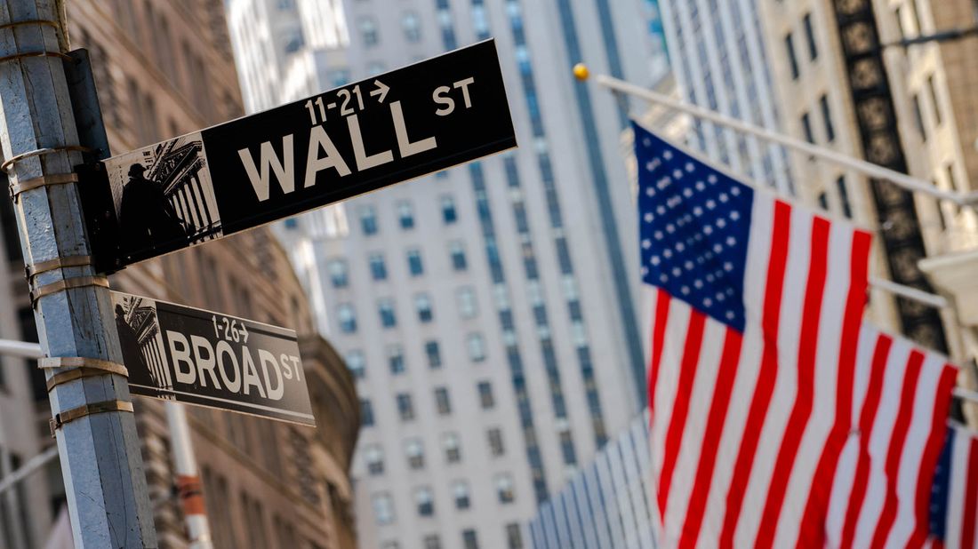 Wall Street and Broad Street signs with an American flag in the background