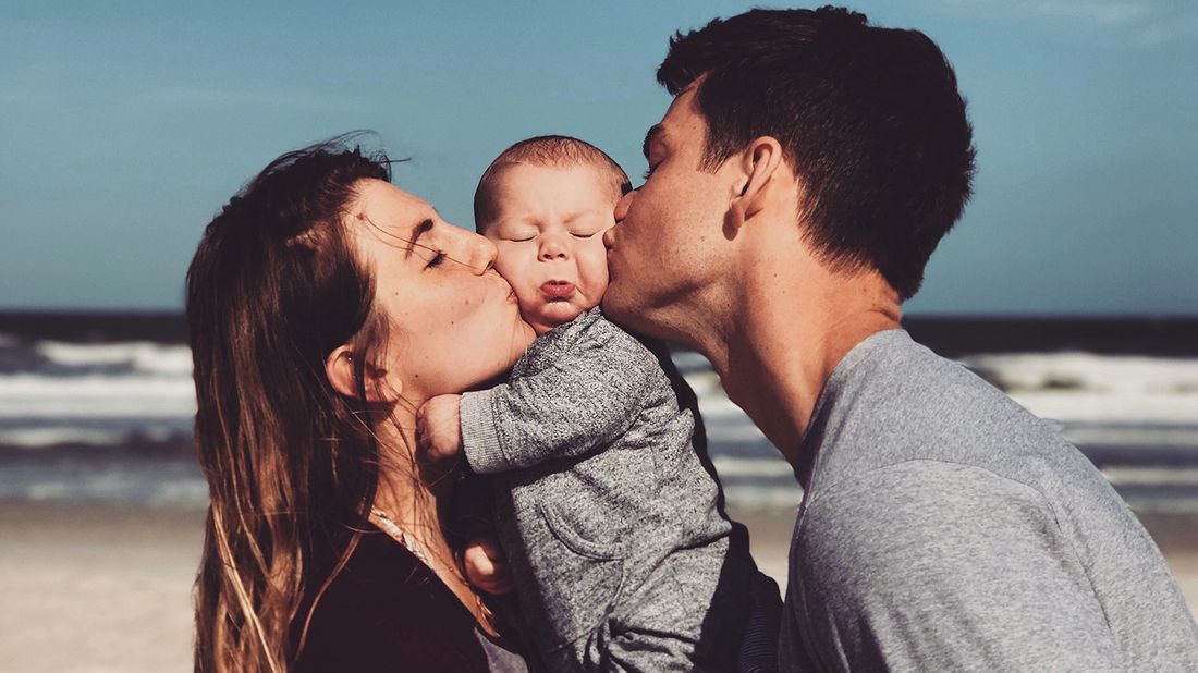 parents and newborn on the beach