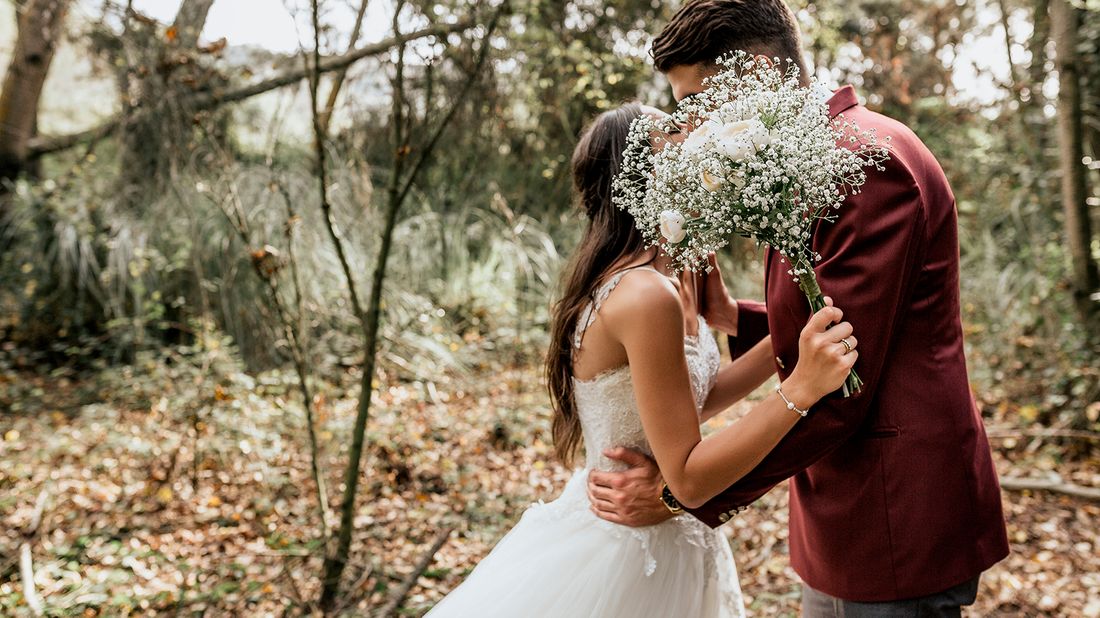 bride and groom kissing behind bouquet