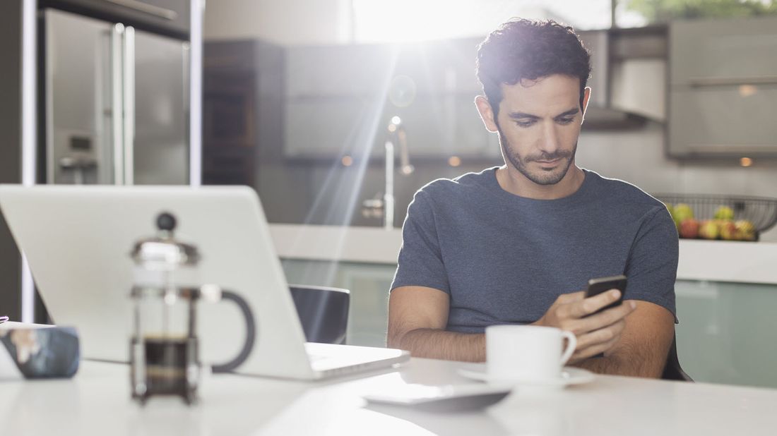 Man looking at cell phone in his kitchen.