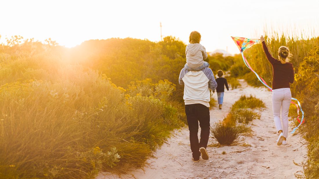 family walking on beach with kite