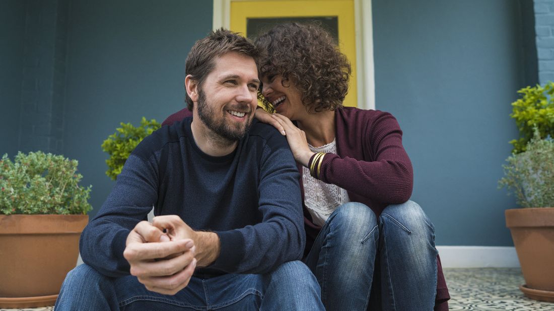 Couple sitting in front of house.