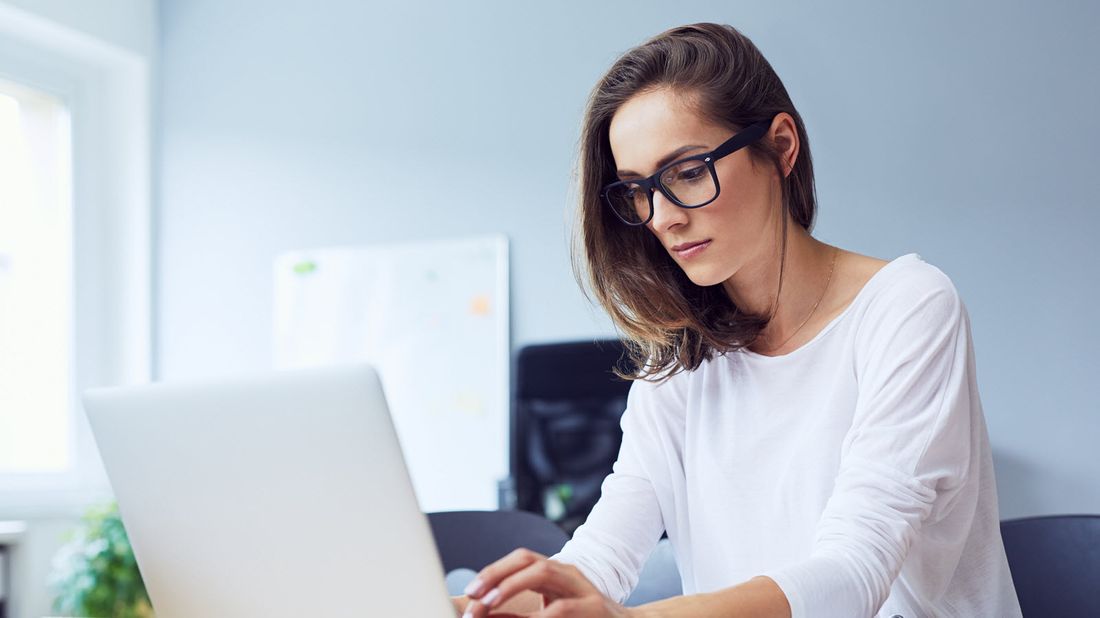 A woman with glasses working on laptop