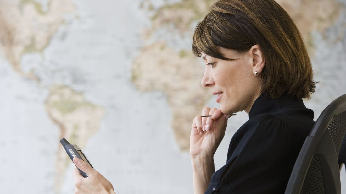 A woman reading her phone in front of a world map