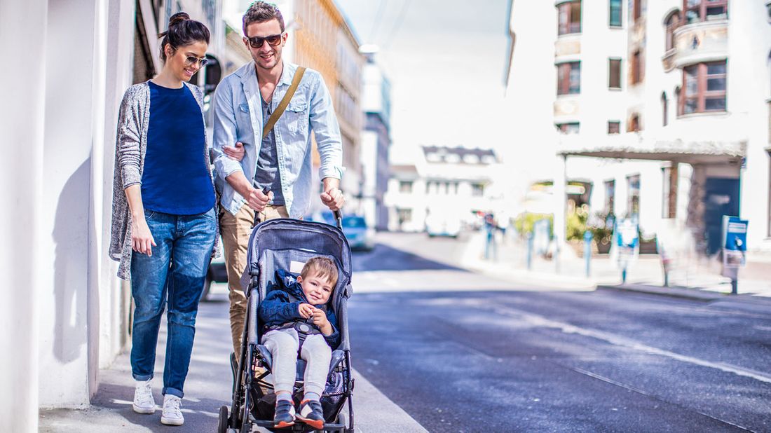 parents pushing toddler in stroller along sidewalk