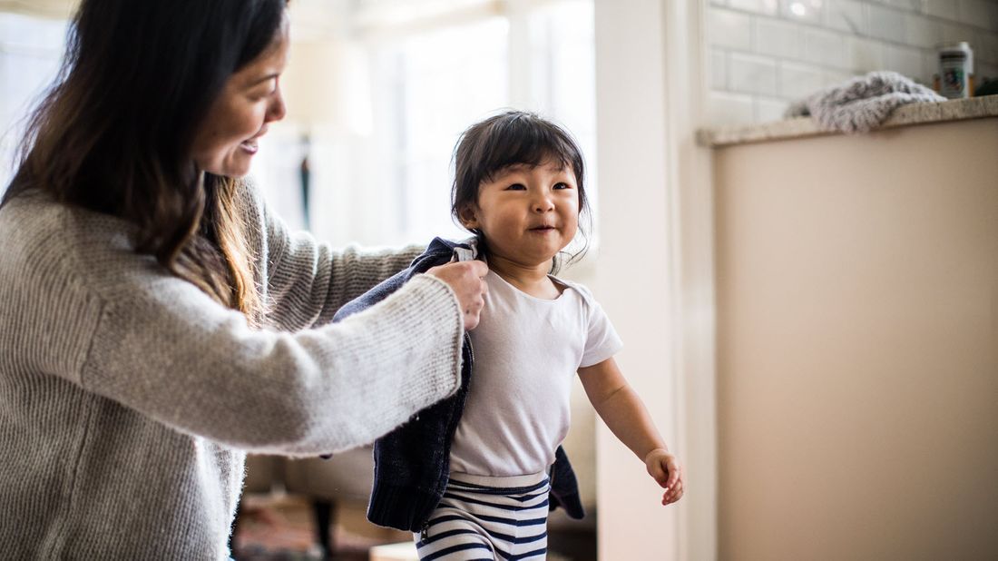 Mom putting a coat on her daughter.