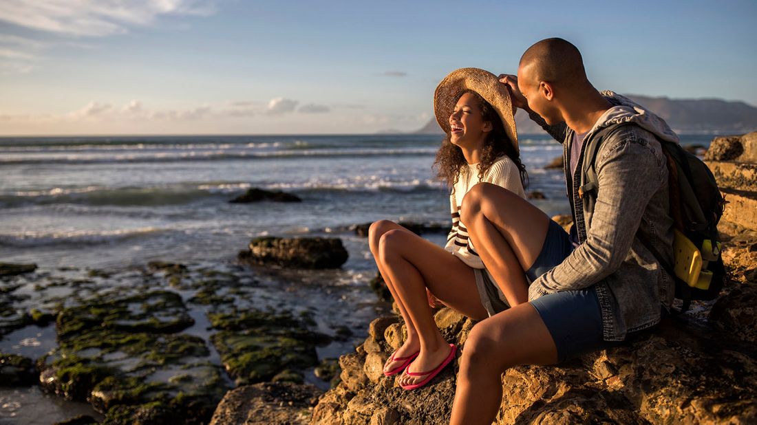 couple sitting on rocks by ocean