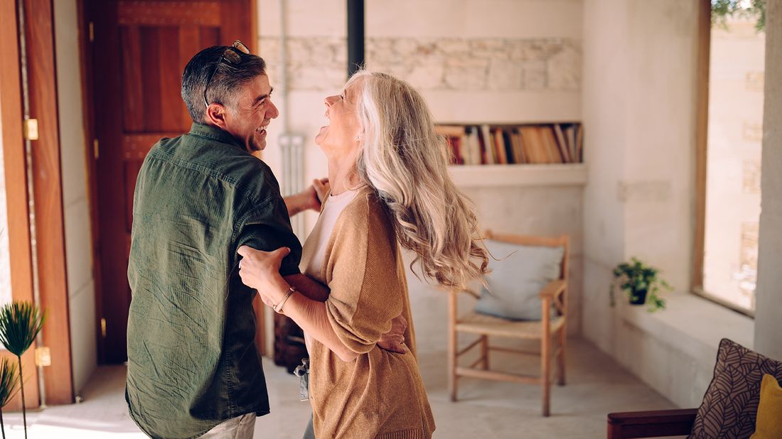 happy senior couple dancing in living room 