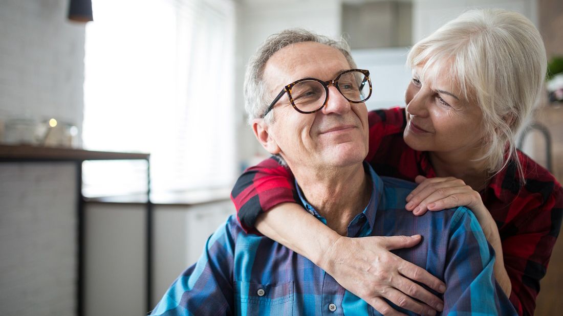 Senior man and woman hugging in their home discussing reverse mortgages.