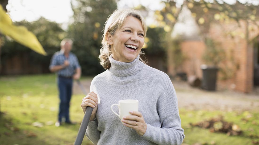 Woman raking leaves, considering annuity stereotypes.